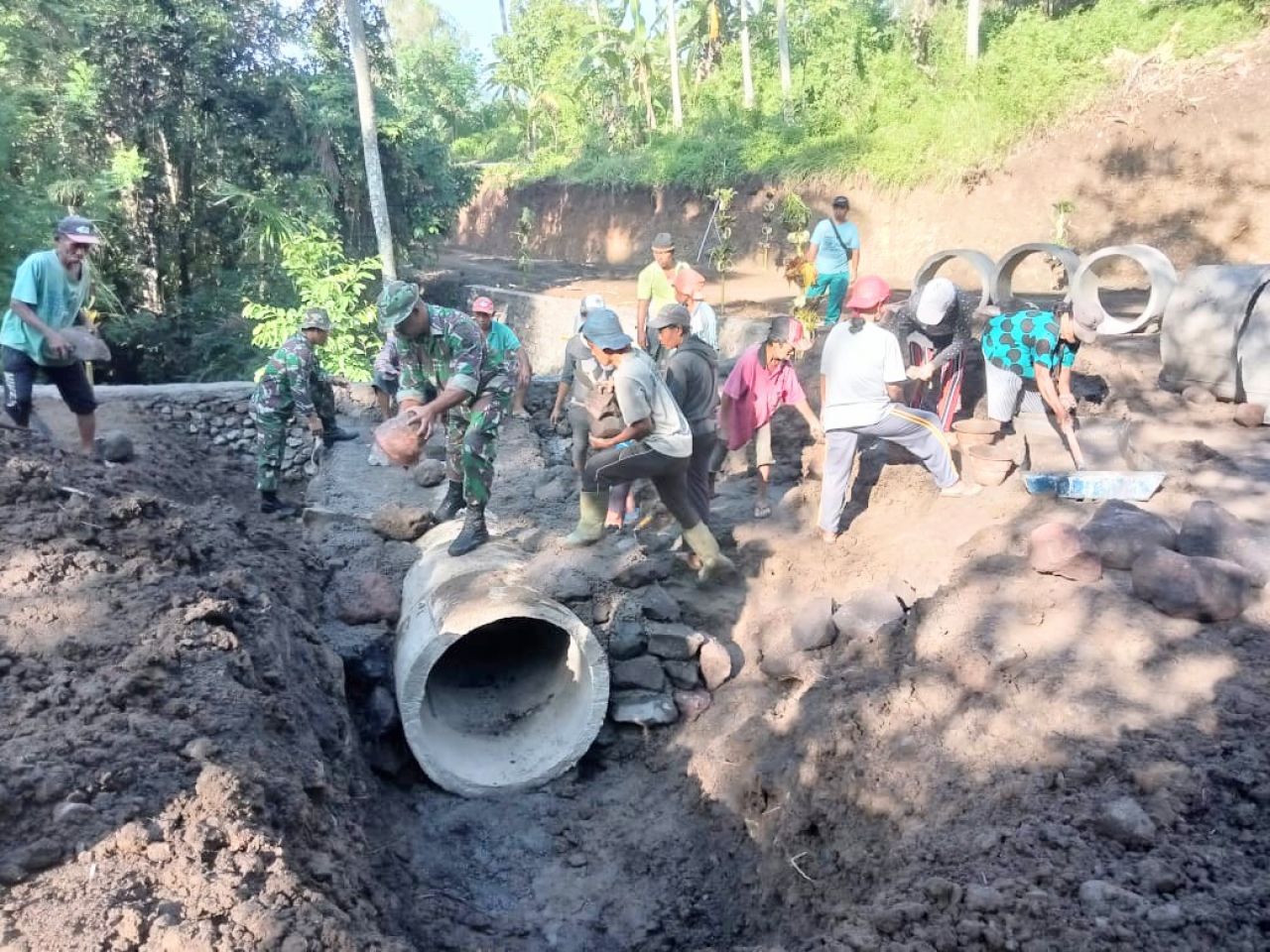 Satgas TMMD Dibantu Warga Bergelut Dengan Material Dan Suara Mesin Molen Agar Program TMMD Selesai Tepat Waktu