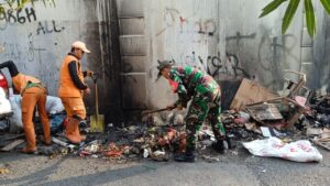 Babinsa Kelurahan Pulogebang Bersihkan Sampah Yang Menumpuk