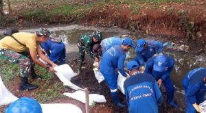 Kolaborasi Babinsa Kelurahan Lubang Buaya Bersama Petugas Dinas Tata Air Bersihkan Saluran Air